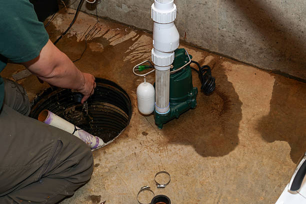 a plumber repairing a sump pump in a flooded basement in a residential home a plumber repairing a sump pump in a flooded basement in a residential home